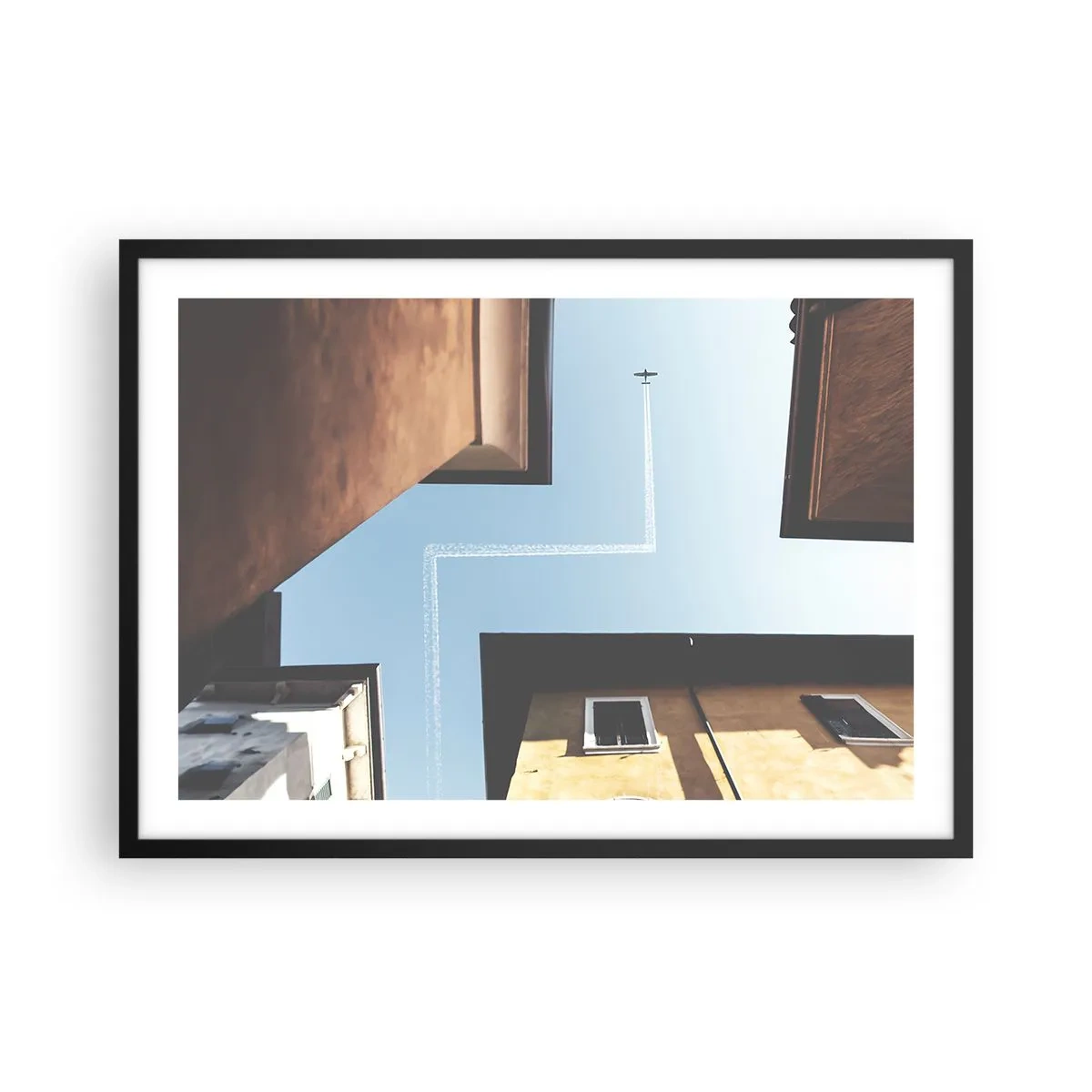 Póster en marco negro - Vista del avión y su estela en el cielo desde una perspectiva callejera. - 70x50cm - Por encima del laberinto urbano - Decoración de pared moderna para salón y dormitorio ARTTOR